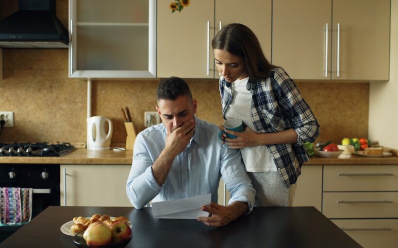 Un couple examine des documents et calculs liés à l'impôt sur le revenu à la maison