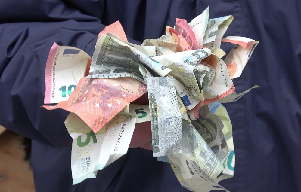 Une main tenant plusieurs billets en euros froissés